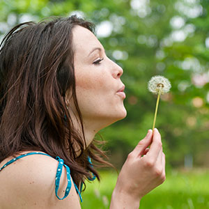 woman blowing a dandelion